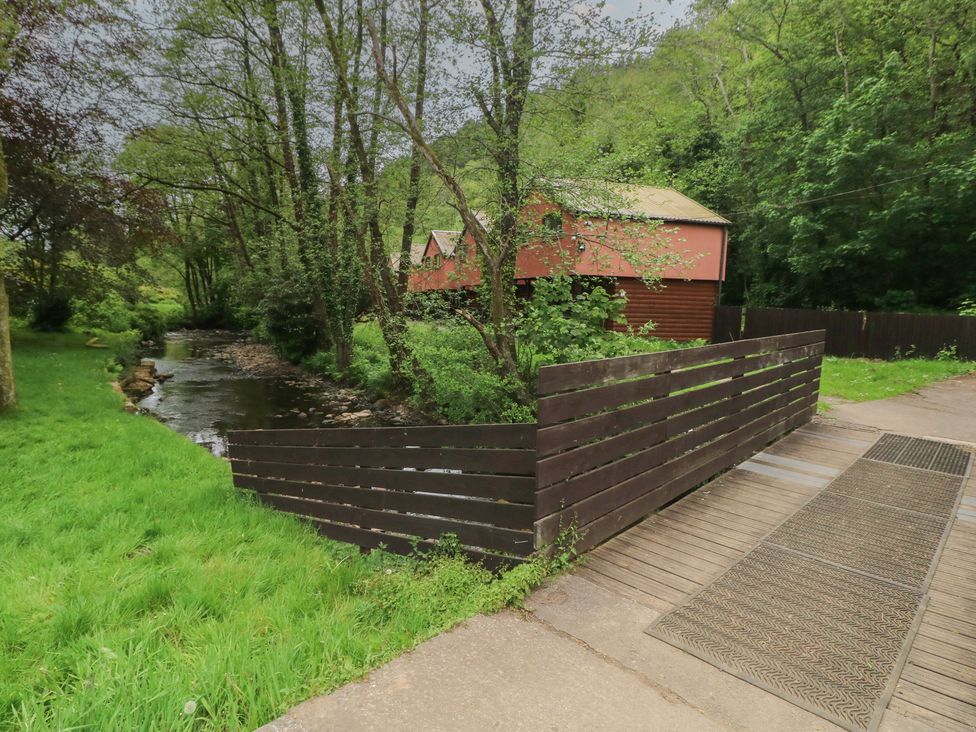 A stream with a wooden fence and cabin at Cabin No. 16 - Salt and Fern Cabins Goytre near Port Talbot