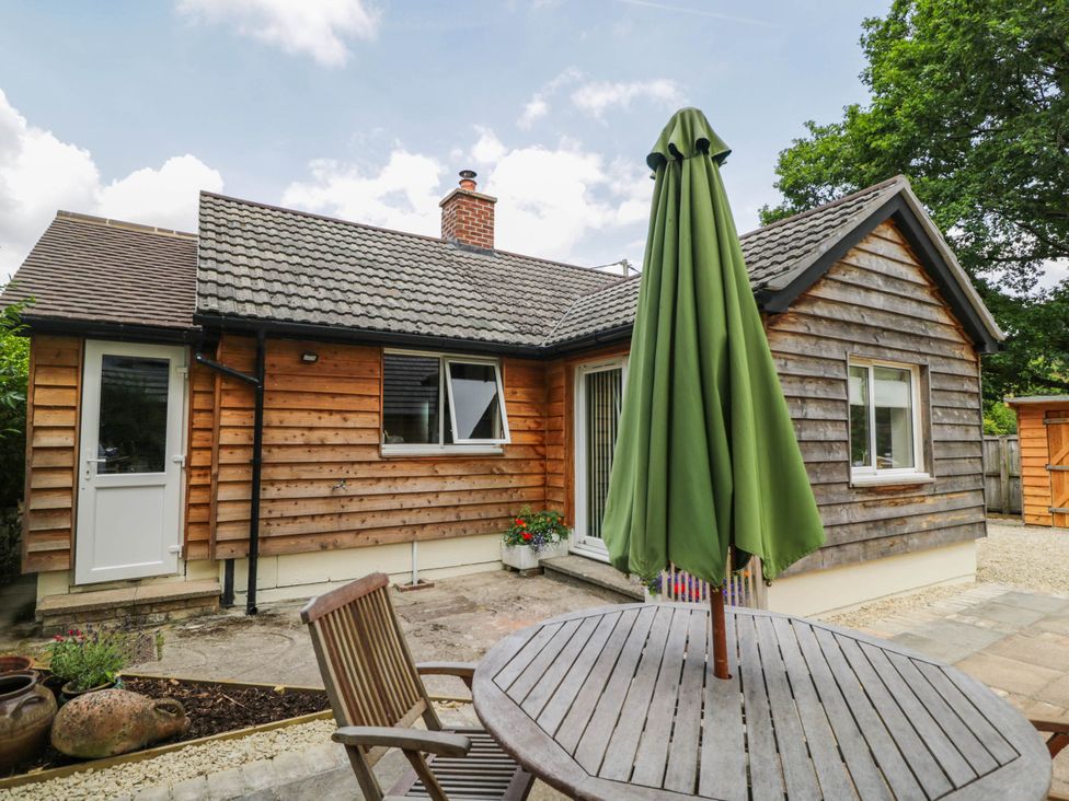 An outdoor area with a wooden house and a table with an umbrella at Little Orchard in SwallowCliffe