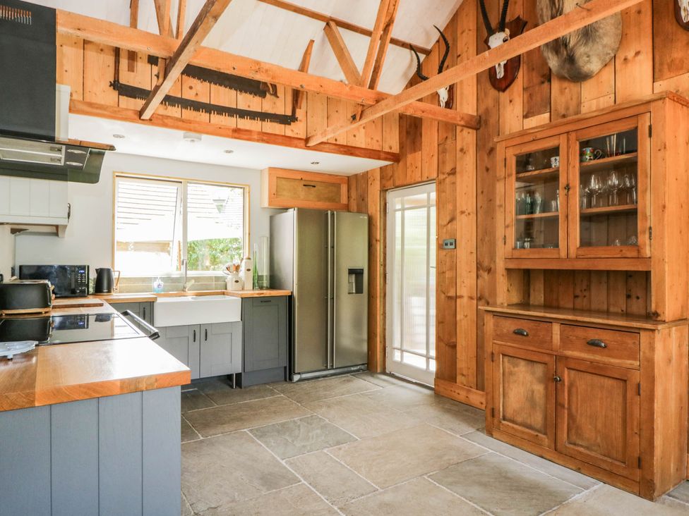A kitchen with wooden cabinets and appliances at Little Orchard in SwallowCliffe