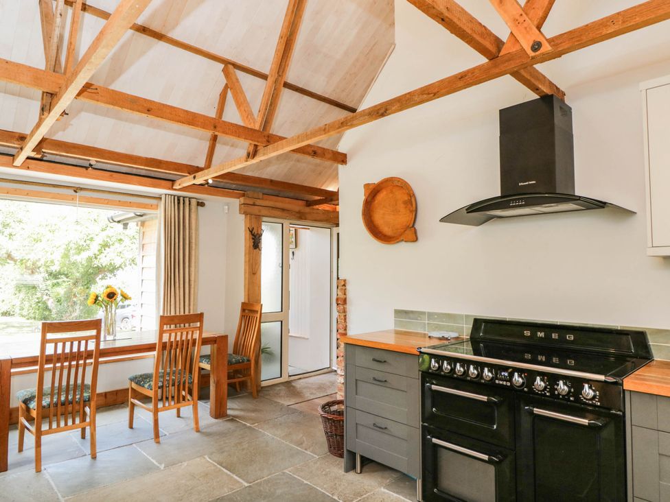 A kitchen with a window, table, chairs, and an oven at Little Orchard in SwallowCliffe