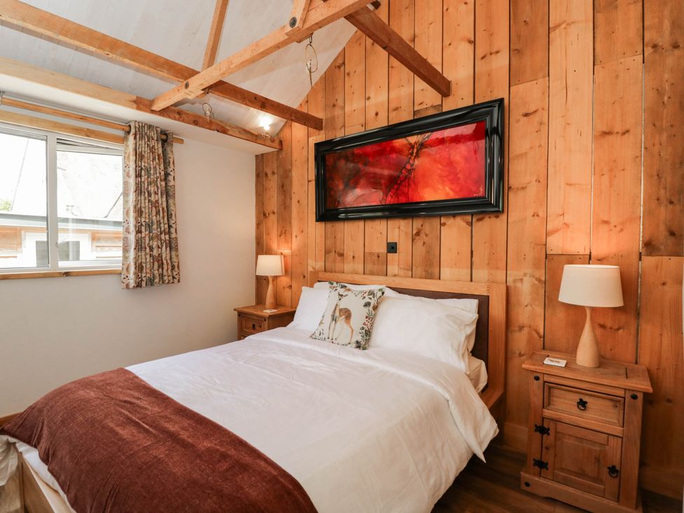 A bedroom with a bed and bedside table at Little Orchard in SwallowCliffe