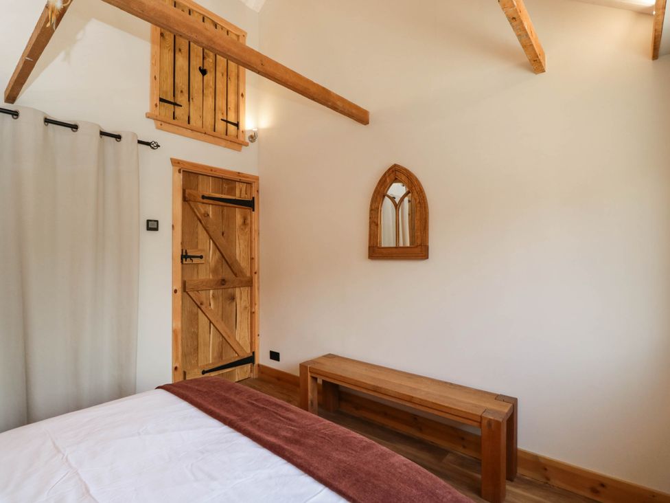 A bedroom with a wooden door and a mirror at Little Orchard in SwallowCliffe