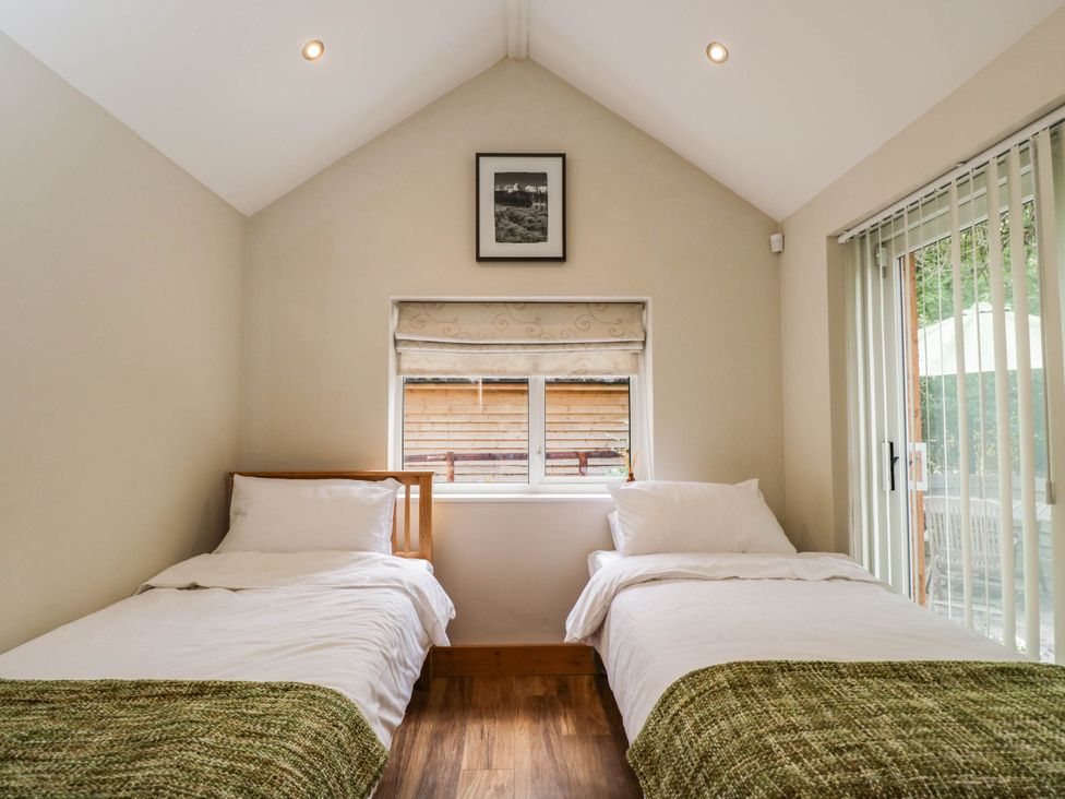 A bedroom with two beds and a window at Little Orchard SwallowCliffe