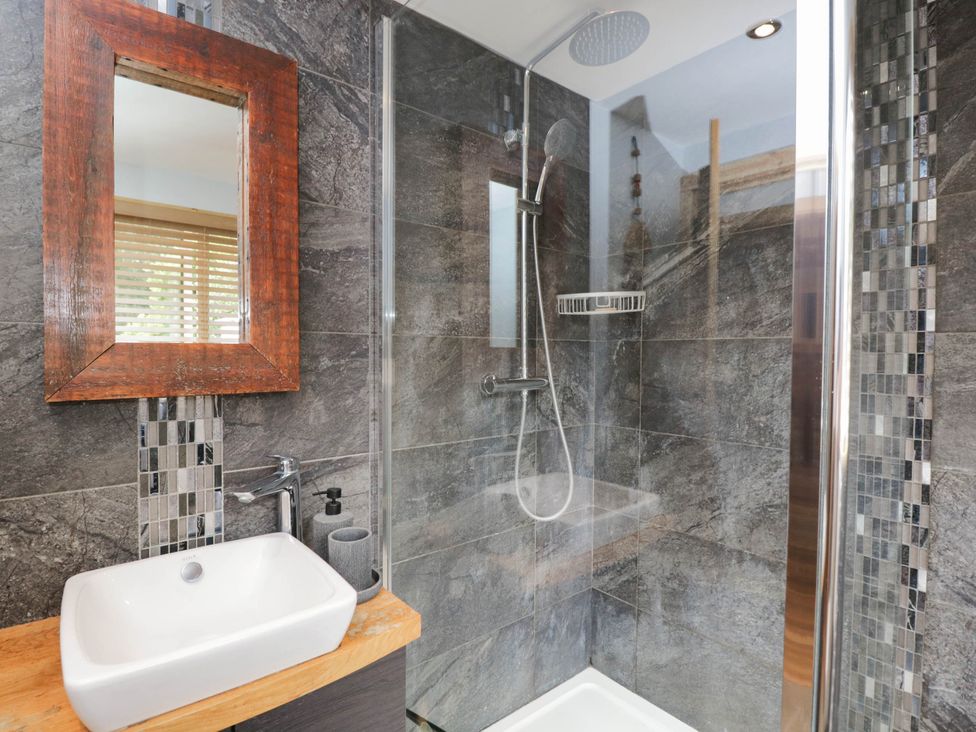 A shower with a sink and mirror in the bathroom at Little Orchard in SwallowCliffe