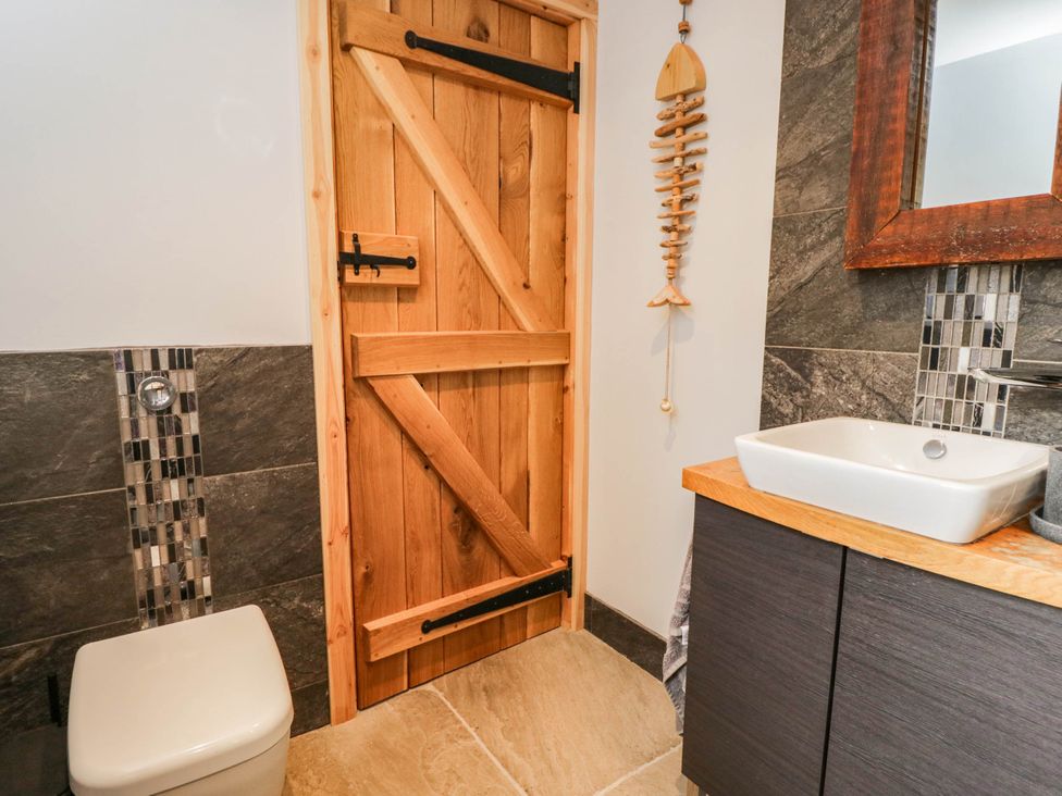 A bathroom with a wooden door, sink and toilet at Little Orchard in SwallowCliffe