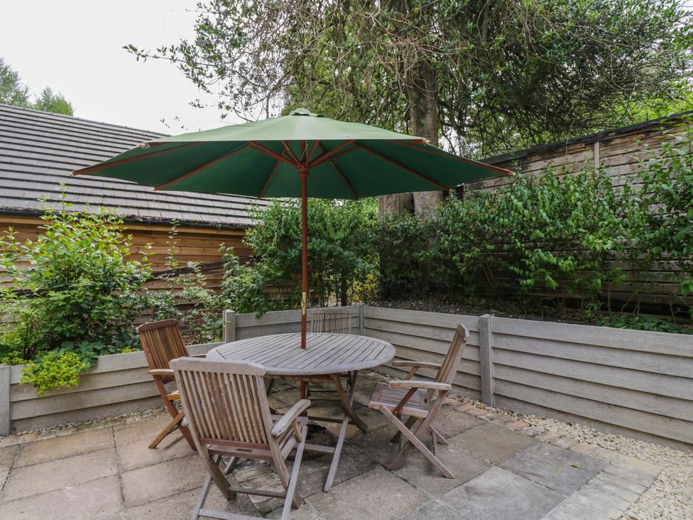 A garden with a table and chairs under an umbrella at Little Orchard in SwallowCliffe