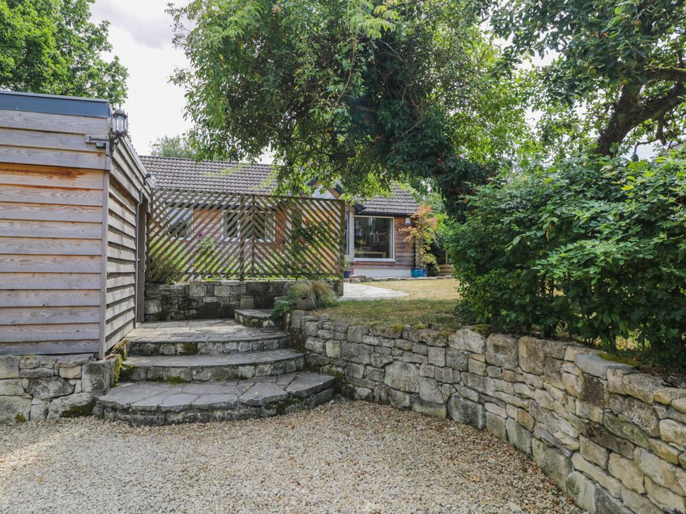 A garden area with stone steps and a wooden fence at Little Orchard in SwallowCliffe