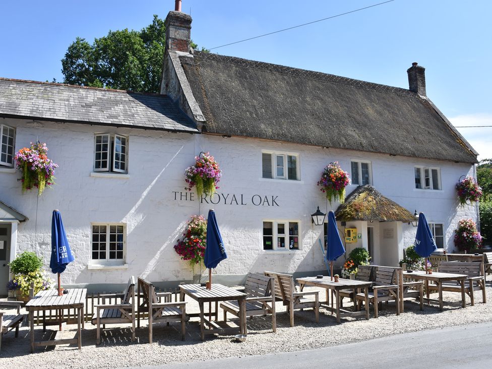 A pub exterior with outdoor seating and flower pots at The Royal Oak in SwallowCliffe