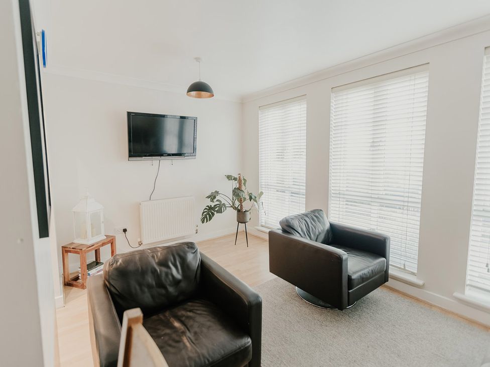 A living room with a television and chairs at 5 Mariners Wharf in Newhaven