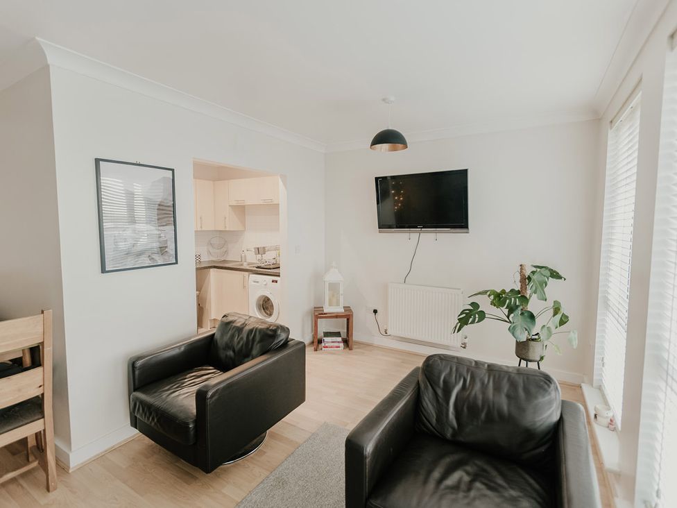 A living room with black leather armchairs and a television at 5 Mariners Wharf in Newhaven
