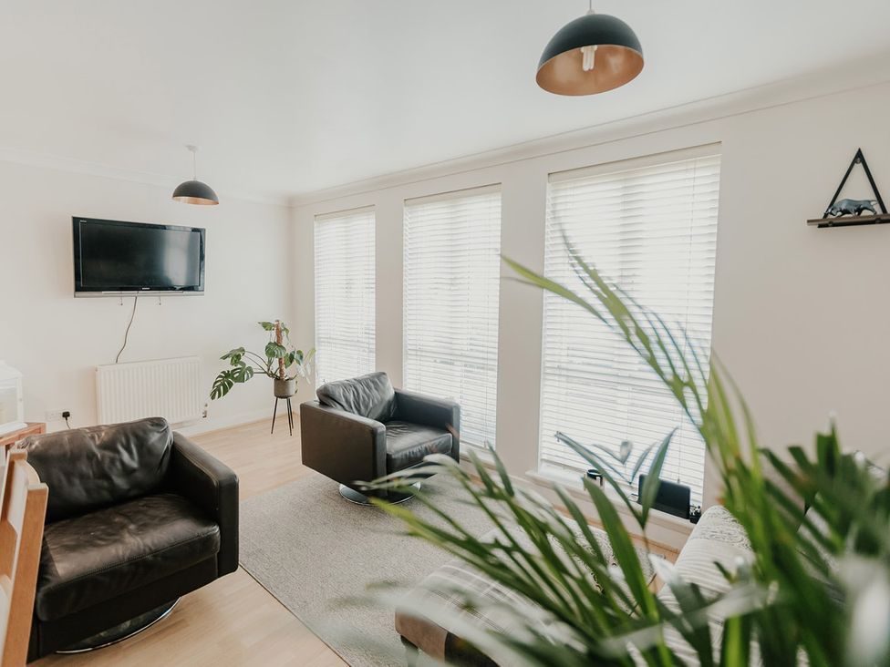 A living room with a television and two armchairs at 5 Mariners Wharf Newhaven