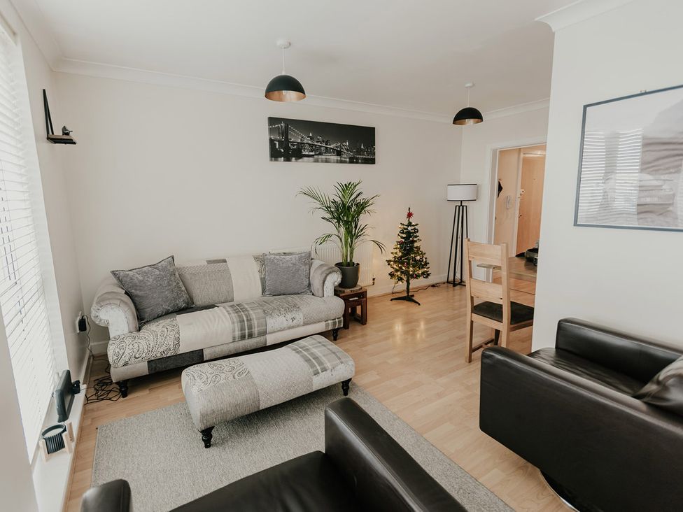 A living room with a sofa, coffee table, plant, and Christmas tree at 5 Mariners Wharf Newhaven