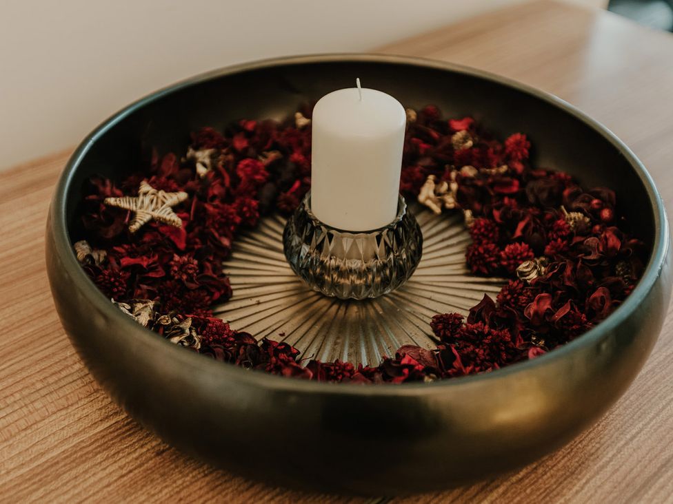 A decorative bowl with a candle and dried flowers