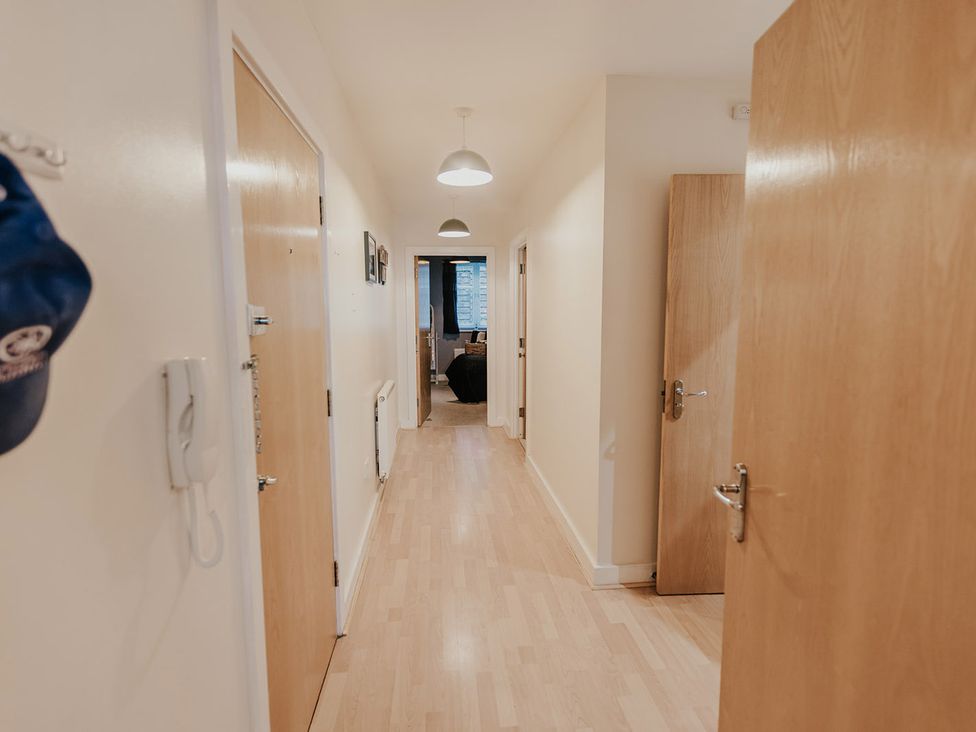 A hallway with doors and framed pictures at 5 Mariners Wharf in Newhaven