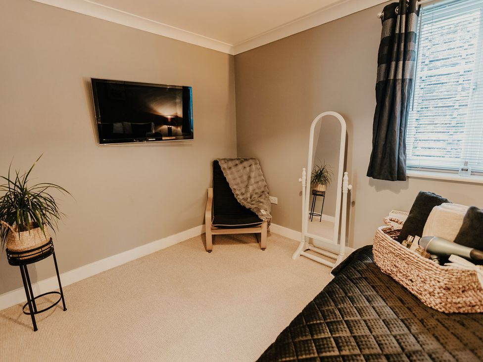A bedroom with a television, chair, and mirror at 5 Mariners Wharf in Newhaven