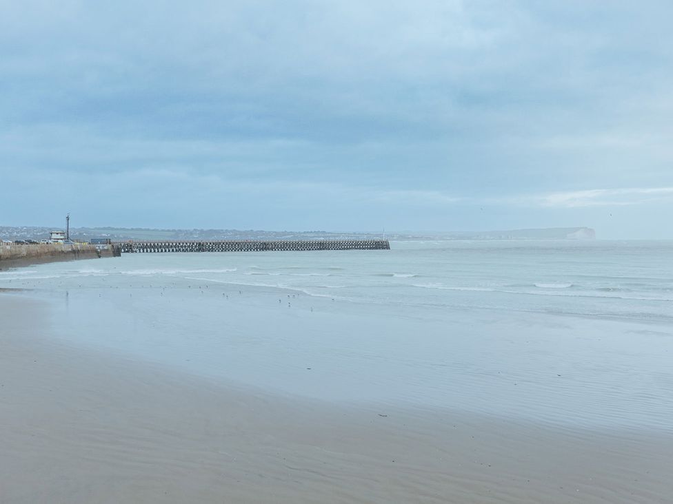 A beach view with a pier in the distance at 5 Mariners Wharf in Newhaven
