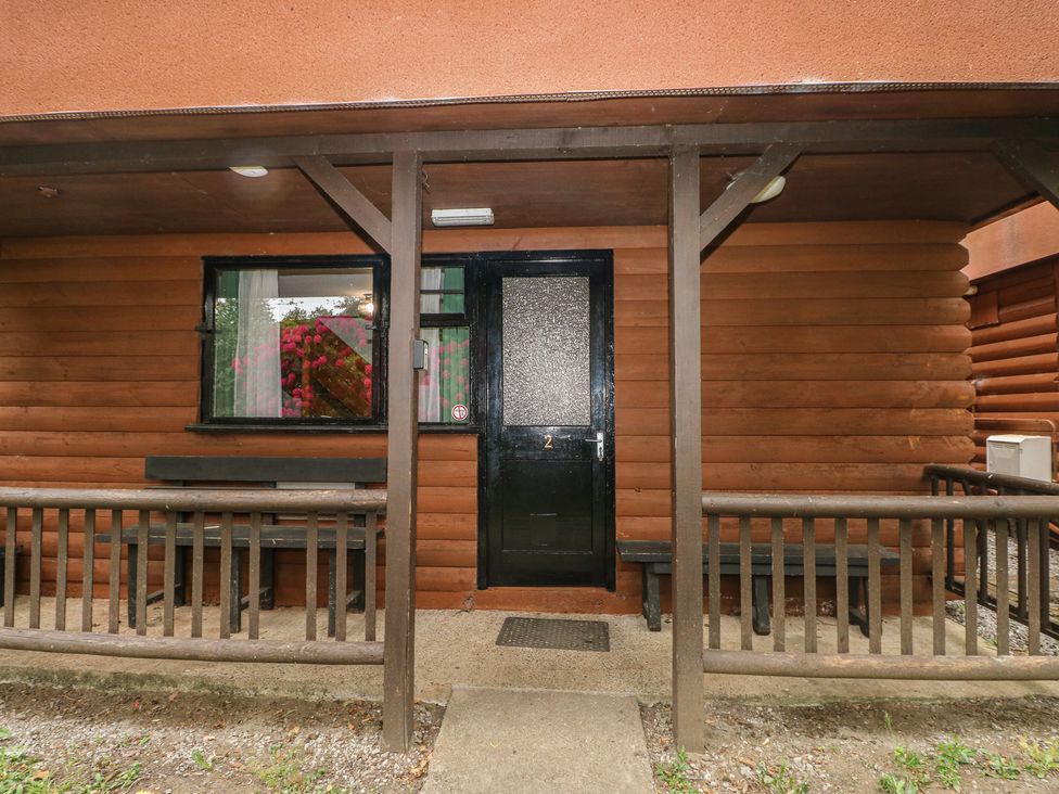An entrance to a cabin with a black door and benches at Cabin No. 2 - Salt and Fern Cabins in Goytre near Port Talbot