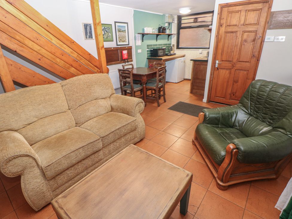 A living room with a sofa, armchair, and coffee table at Cabin No. 2 - Salt and Fern Cabins Goytre near Port Talbot