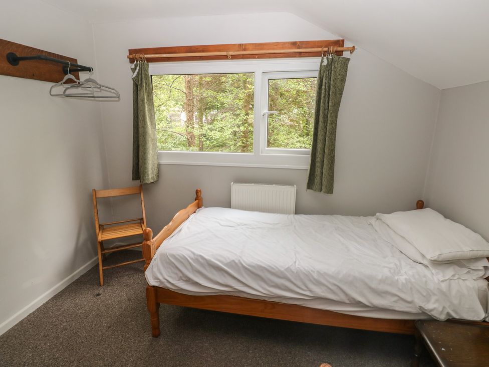 A bedroom with a bed and a chair at Cabin No. 2 - Salt and Fern Cabins Goytre near Port Talbot