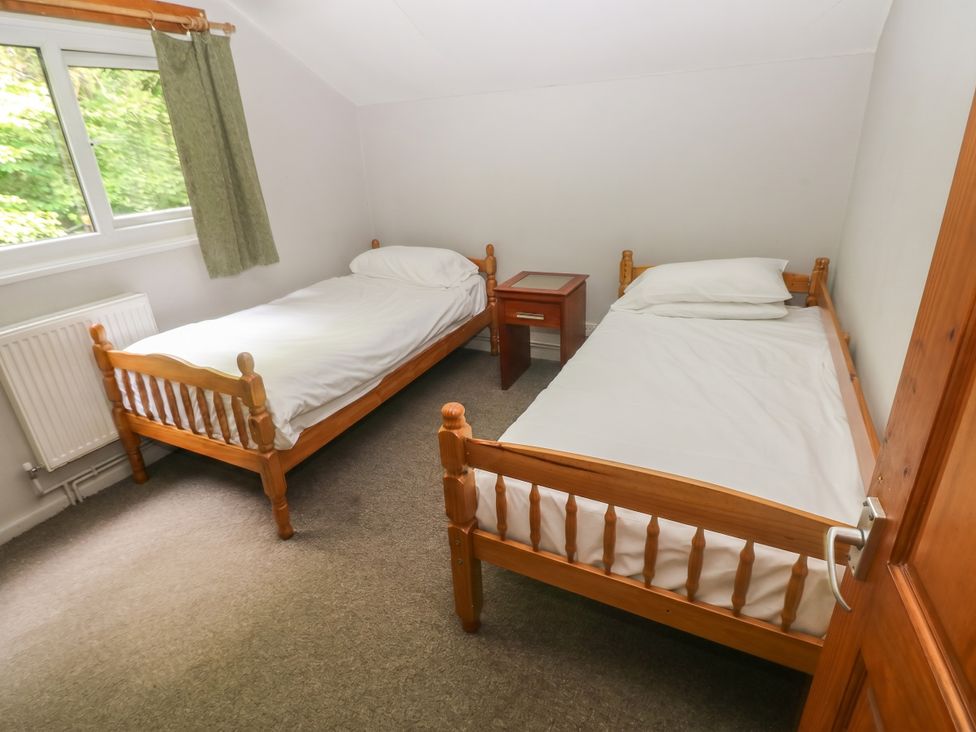 A bedroom with two single beds and a nightstand at Cabin No. 2 - Salt and Fern Cabins Goytre near Port Talbot