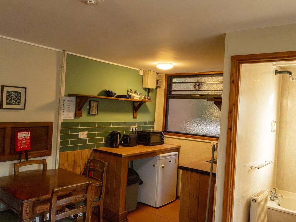 A kitchen with a table, chairs, microwave, and fridge at 3-bedroom cabin (3 of 13) Port Talbot