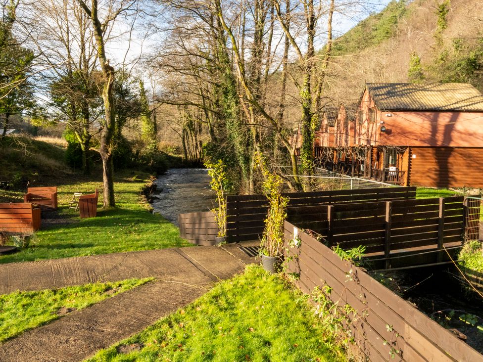 An outdoor area with a stream and wooden cabins at 3-bedroom cabin (3 of 13) Port Talbot