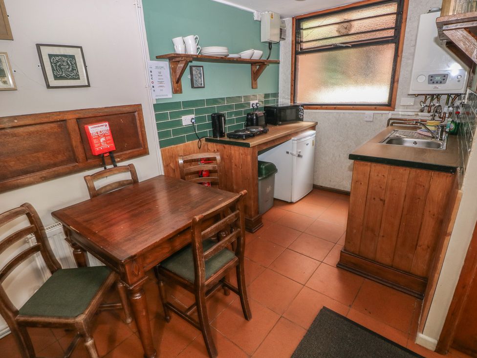 A kitchen with wooden table and chairs at Cabin No. 3 - Salt and Fern Cabins in Goytre near Port Talbot