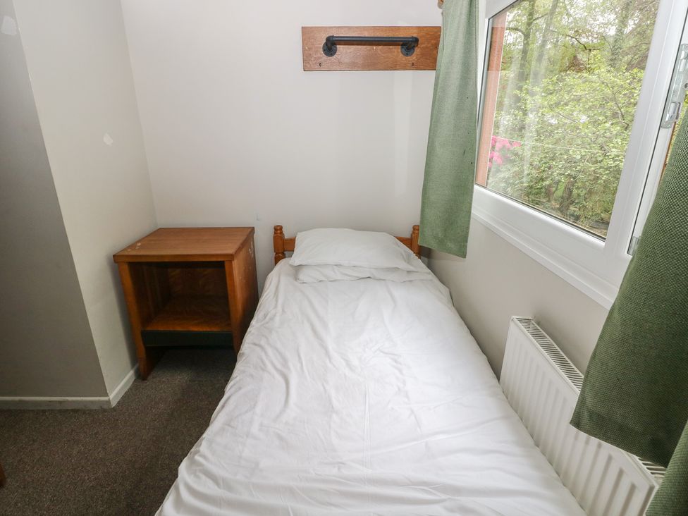 A bedroom with a bed and nightstand at Cabin No. 3 - Salt and Fern Cabins Goytre near Port Talbot