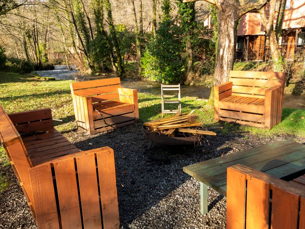 An outdoor area with wooden chairs and a fire pit at 3-bedroom Cabin (4 of 13) Port Talbot