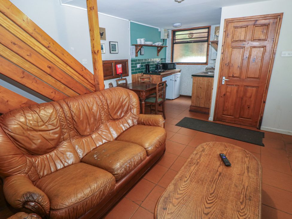 A living room with a sofa and kitchen area at Cabin No. 4 - Salt and Fern Cabins Goytre near Port Talbot