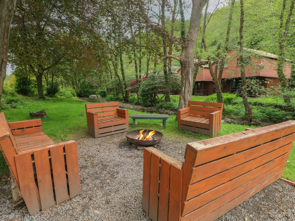 An outdoor area with wooden benches and a fire pit at Cabin No. 4 - Salt and Fern Cabins Goytre near Port Talbot