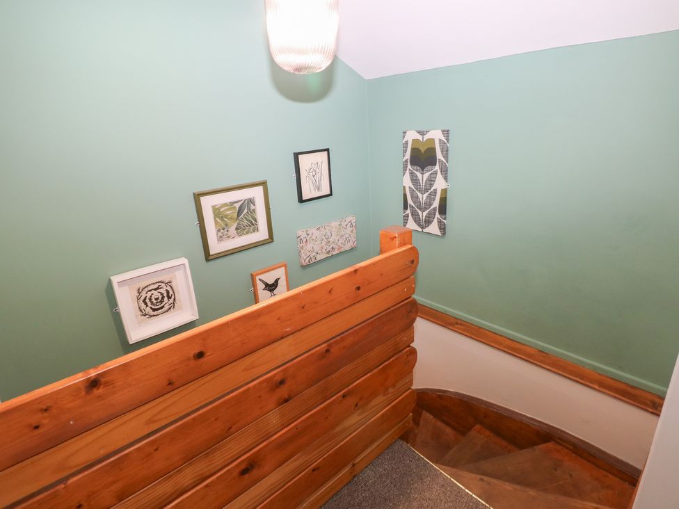 An interior stairwell with a wooden railing and wall art at Cabin No. 5 - Salt and Fern Cabins near Port Talbot