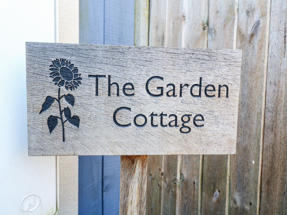 A wooden sign displaying the name The Garden Cottage with a flower design at The Garden Cottage in Hinckley