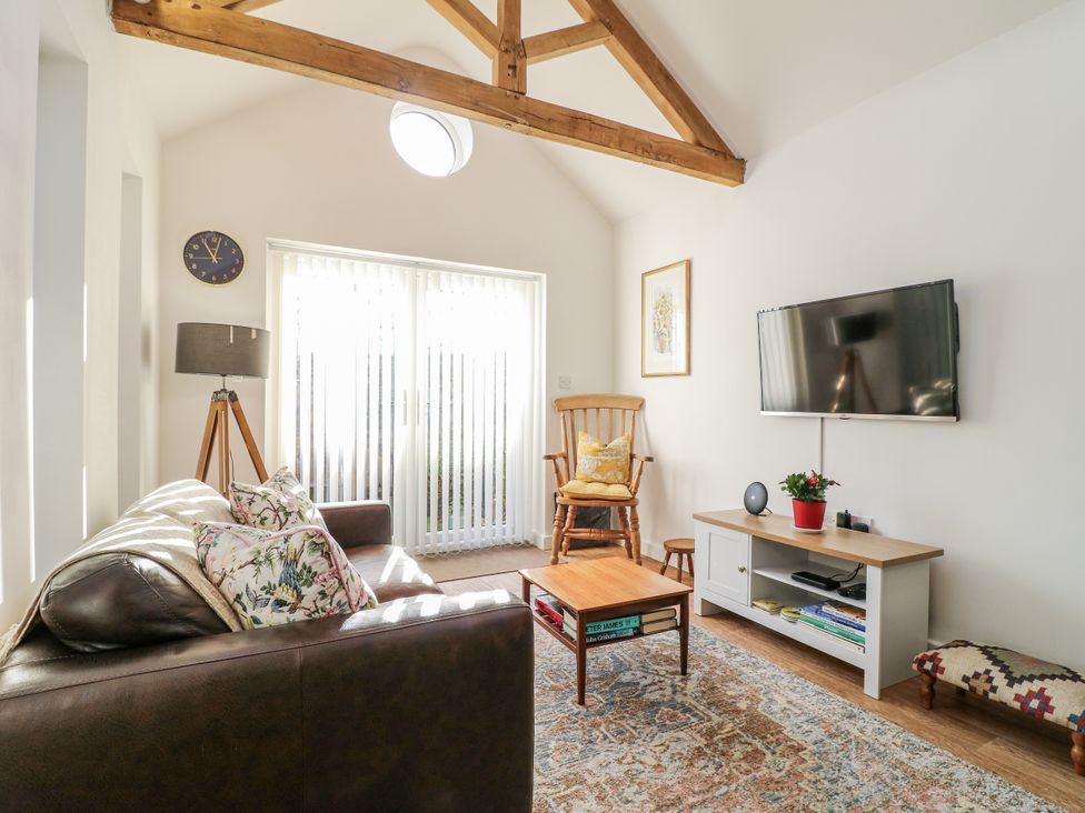 A living room with a sofa, coffee table, and television at The Garden Cottage in Hinckley