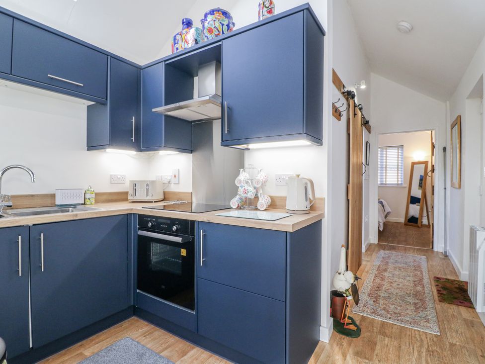 A kitchen with dark cabinets and an oven at The Garden Cottage in Hinckley