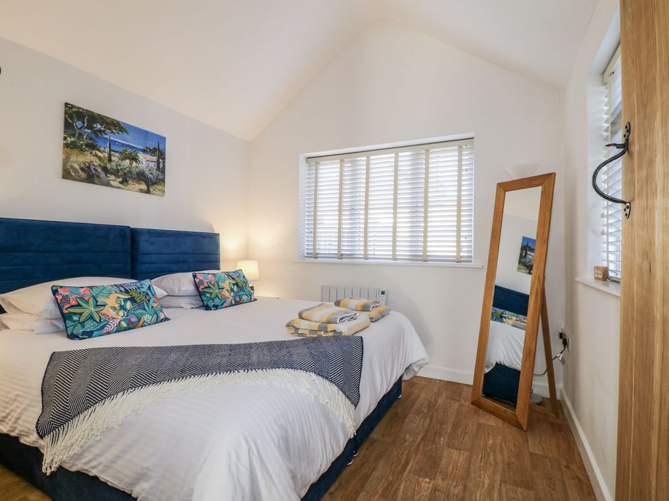 A bedroom with a bed and mirror at The Garden Cottage in Hinckley