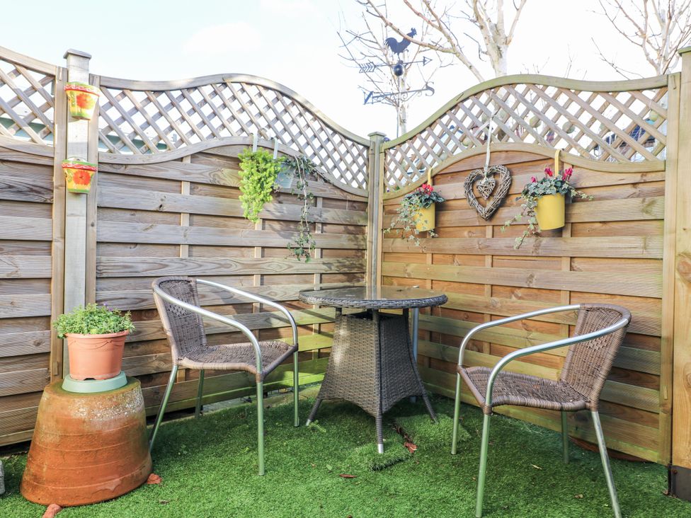 A garden with a table and chairs surrounded by a wooden fence at The Garden Cottage in Hinckley