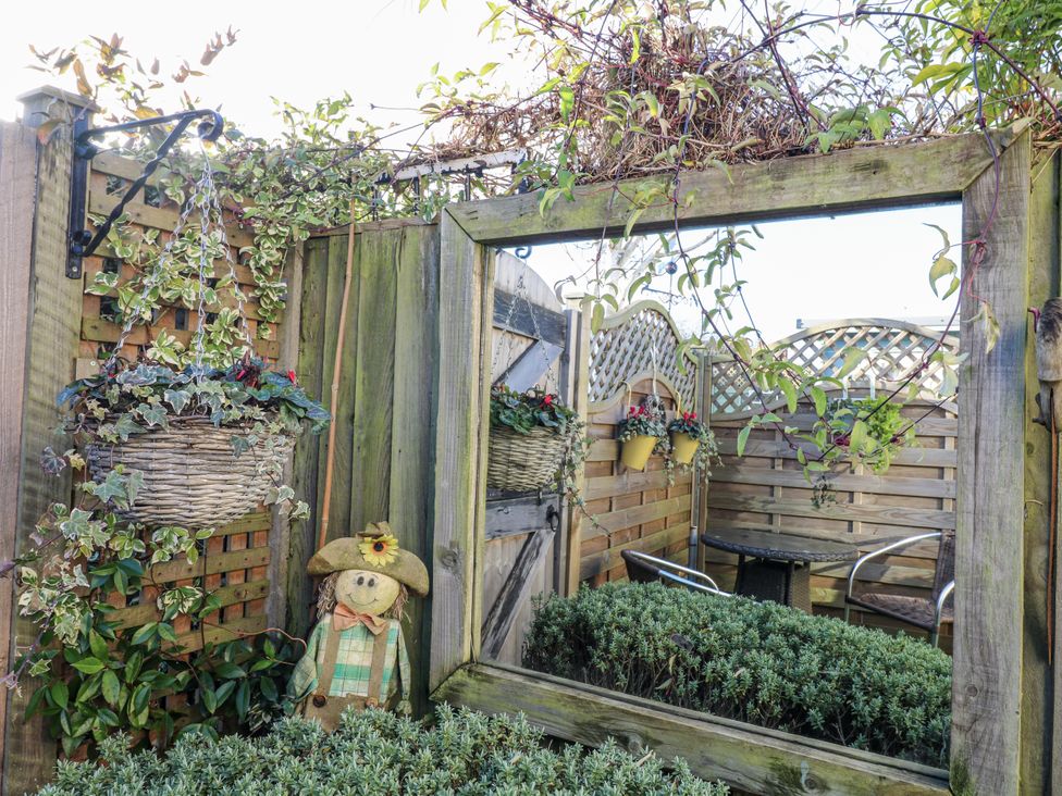 A garden with a mirror frame and a scarecrow at The Garden Cottage in Hinckley