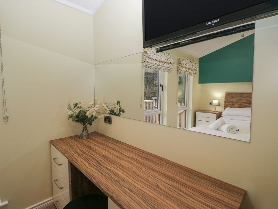A bedroom with a vanity desk and television at High Lake View Lodge White Cross Bay near Troutbeck Bridge