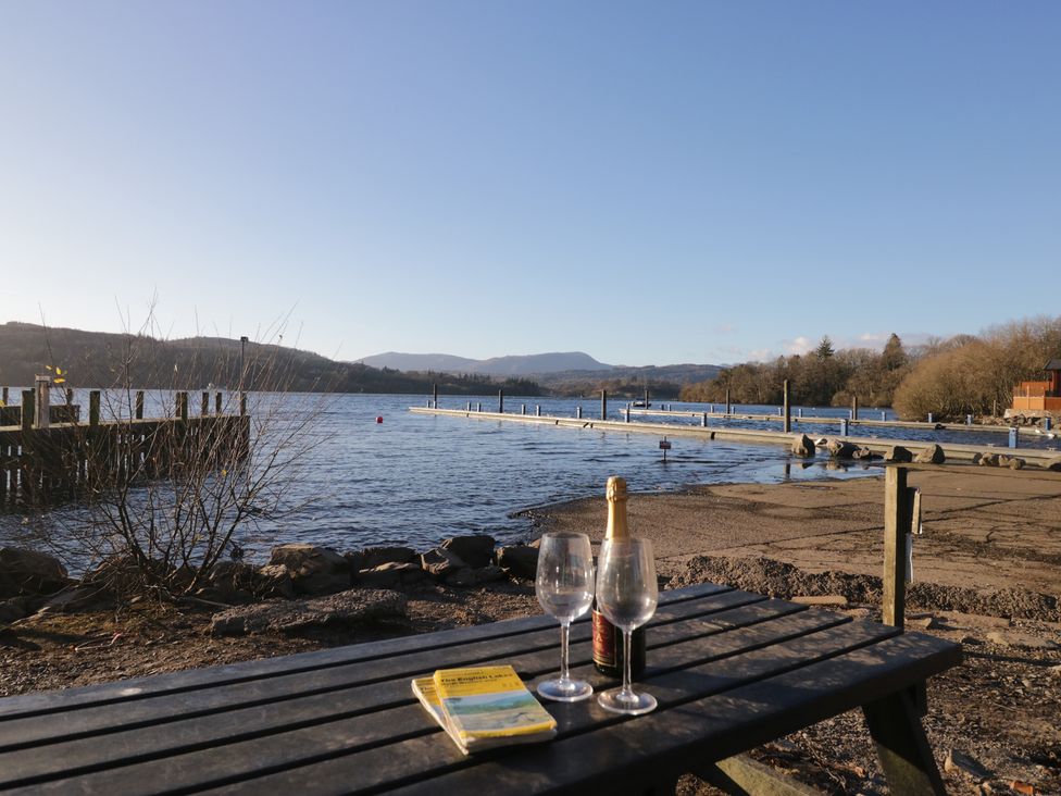 A table with glasses and a bottle by the lake at High Lake View Lodge White Cross Bay near Troutbeck Bridge