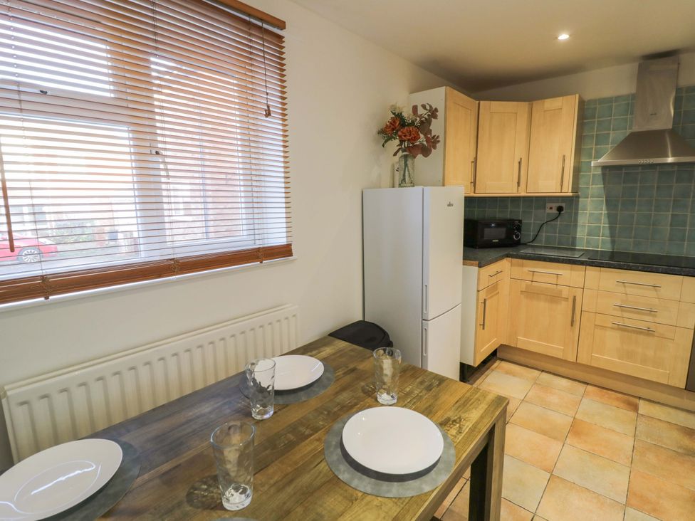 A kitchen with a table and refrigerator at 7 Waverton Mews Royal Leamington Spa
