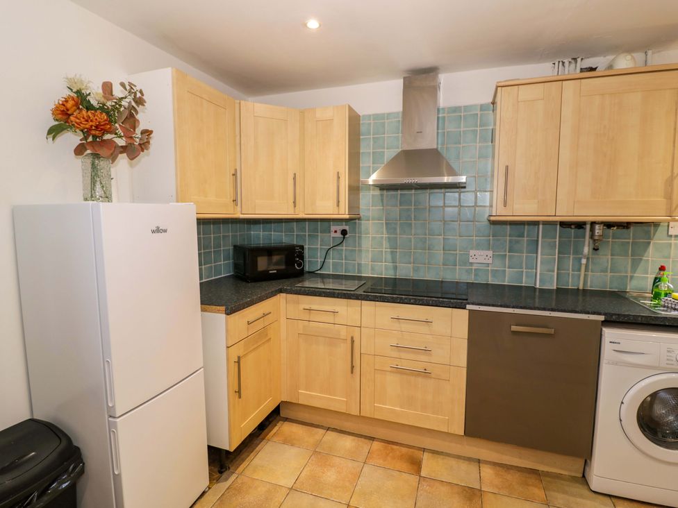 A kitchen featuring appliances and wooden cabinets at 7 Waverton Mews in Royal Leamington Spa