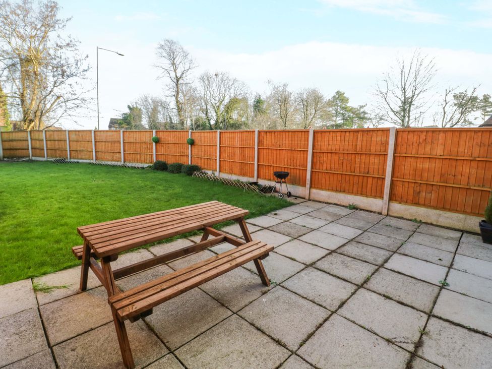 A garden with a wooden table and benches at 7 Waverton Mews in Royal Leamington Spa