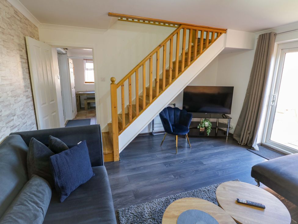 A living room with a staircase and television at 7 Waverton Mews in Royal Leamington Spa