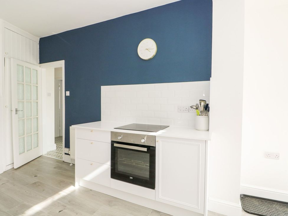 A kitchen with a cooker and wall clock at The Seaside Retreat in Mablethorpe