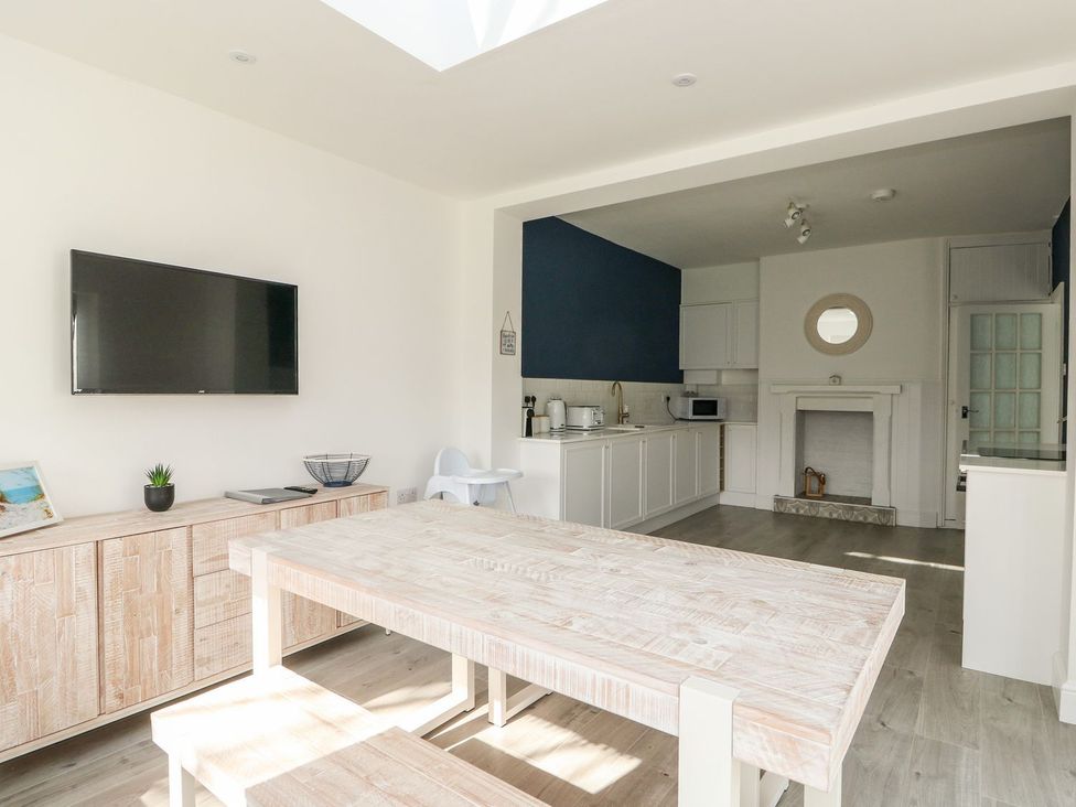 A dining room with a television and a kitchen area at The Seaside Retreat in Mablethorpe
