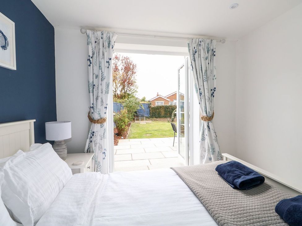 A bedroom with a bed and open door leading to a garden at The Seaside Retreat in Mablethorpe