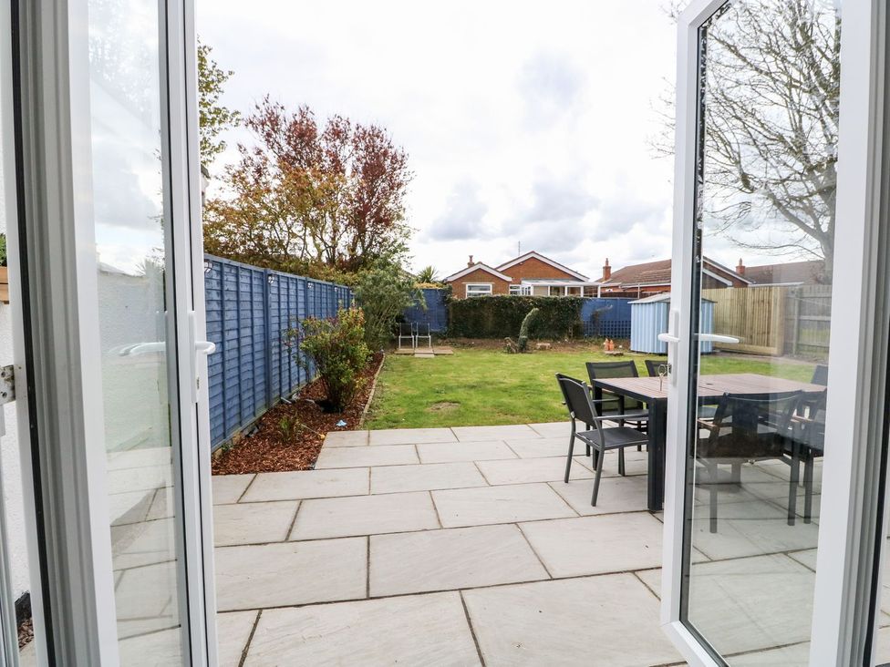 A patio area with chairs and a table overlooking the garden at The Seaside Retreat in Mablethorpe