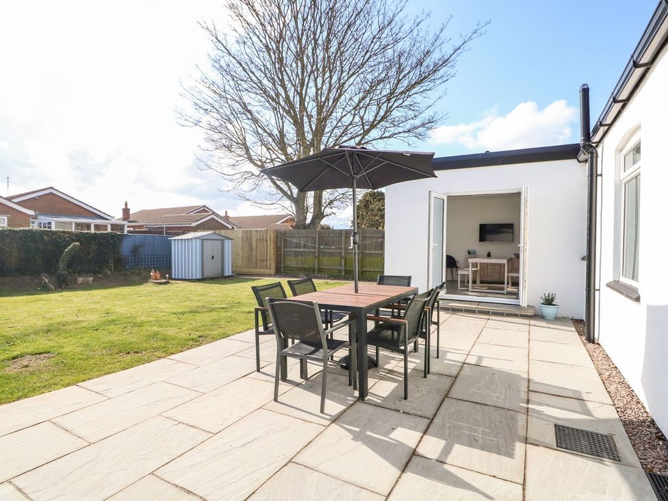 A garden with a table and chairs under an umbrella at The Seaside Retreat in Mablethorpe