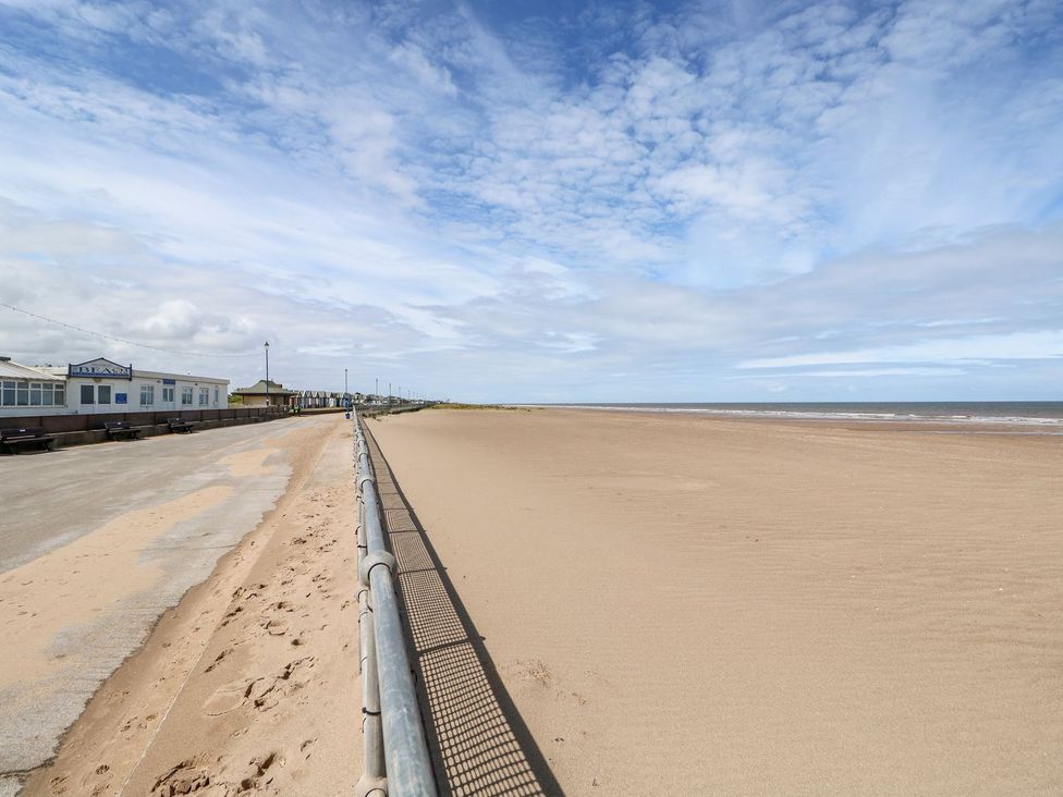 A beach with sand and a walkway at The Seaside Retreat in Mablethorpe